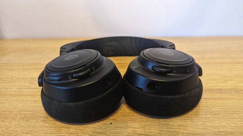 Фотография крупным планом основных чашек SteelSeries Arctis Nova 7 Wireless на столе цвета дуба.